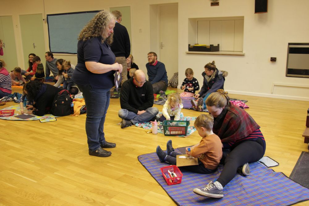 Families sitting on the floor taking part in Early Birds New Worshipping Community