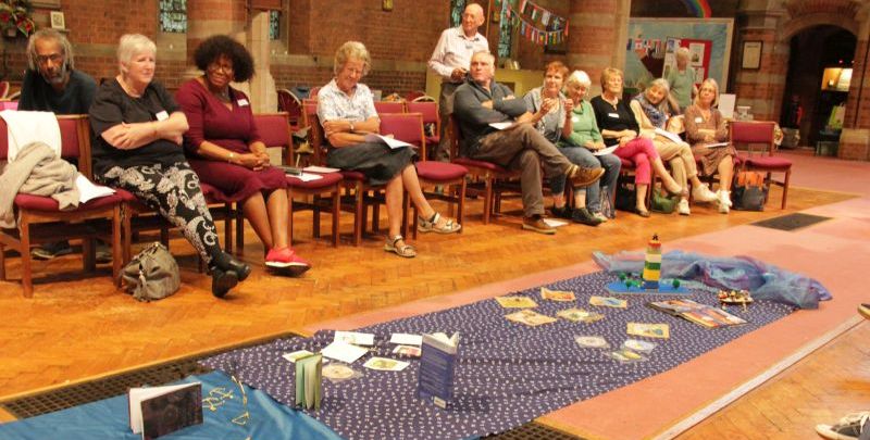 At one activity table participants bend wire with pliers into the shape of anchors, while chatting together