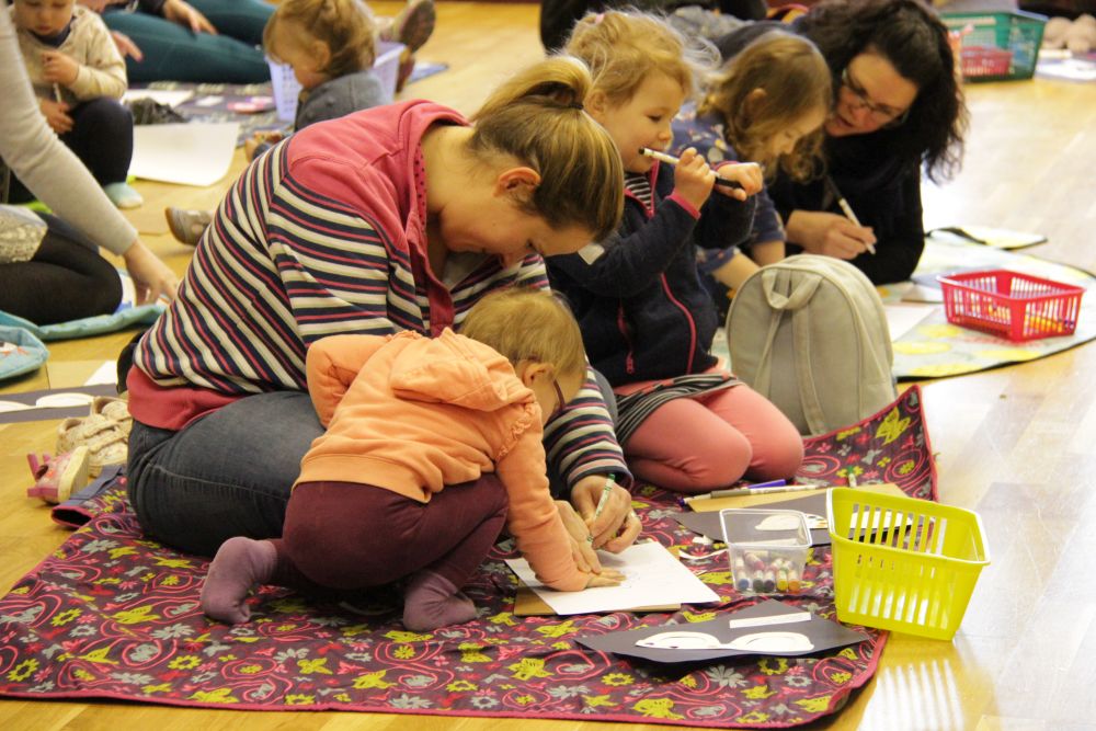 Families sitting on the floor taking part in Early Birds New Worshipping Community