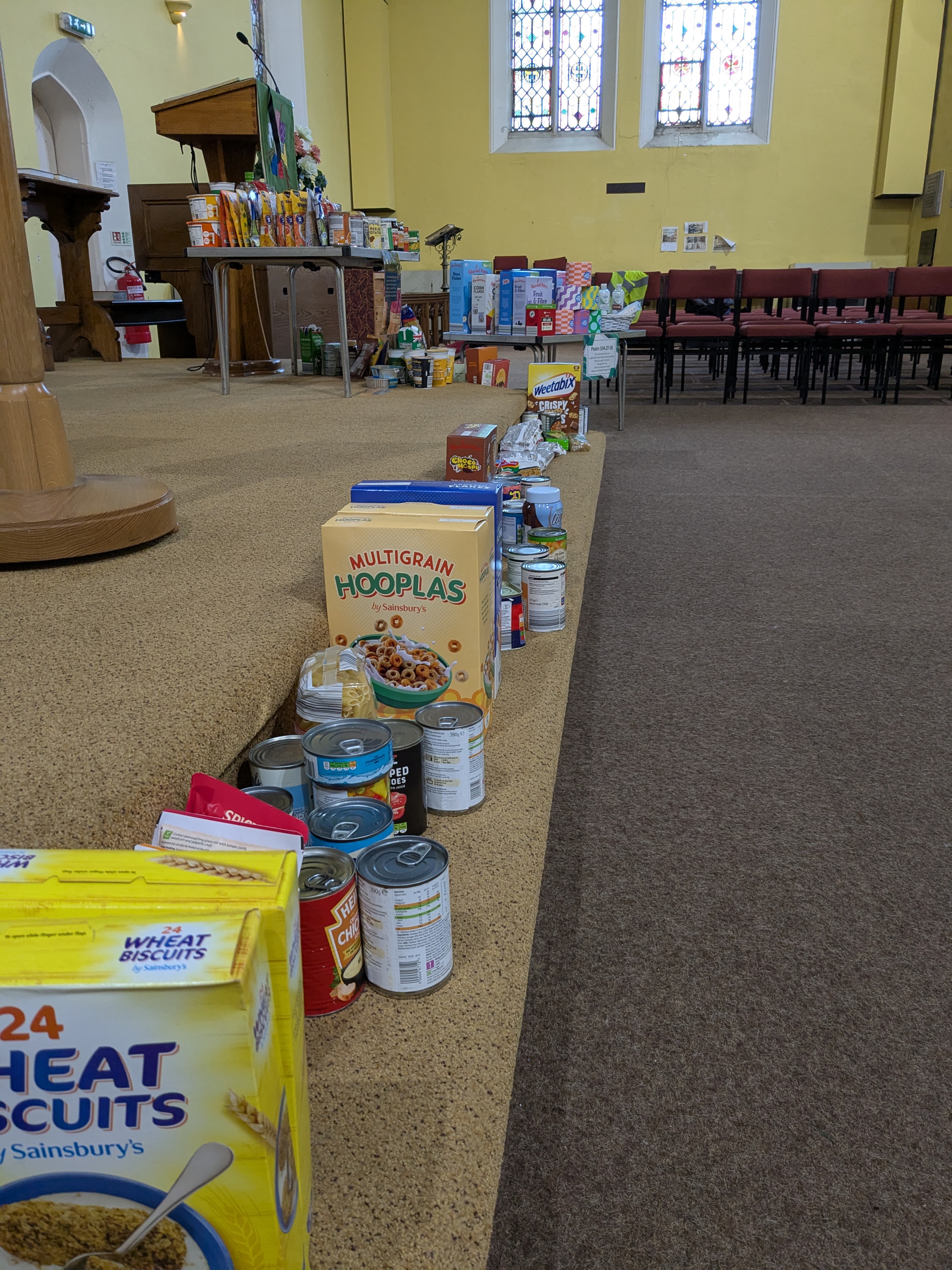 A row of harvest gifts on the step in front of the altar at Lye church