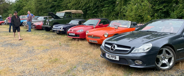 Another view of the classic cars with people walking past