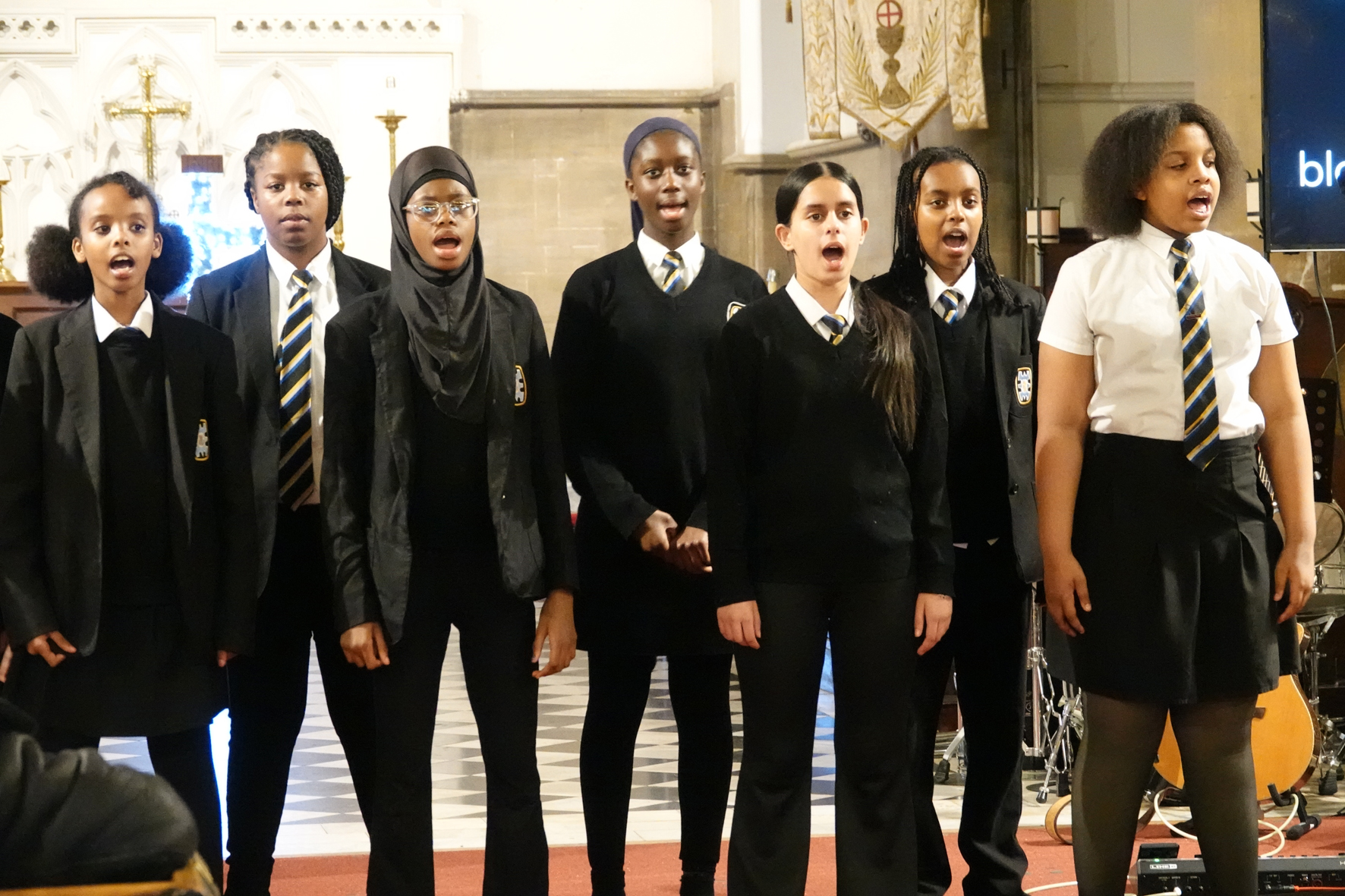 Seven girls from Broadway Academy school choir singing at the front of church