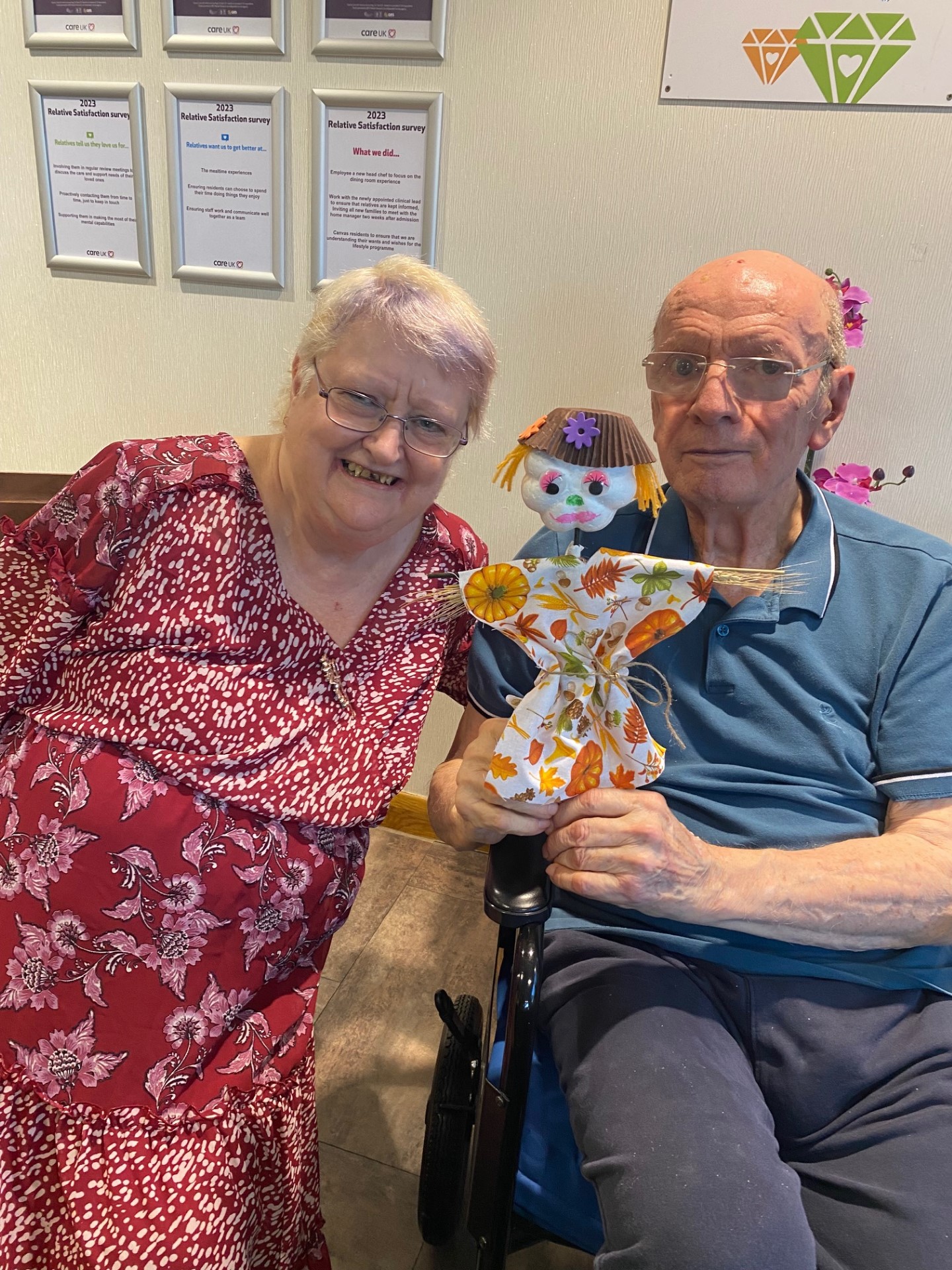 Two people from Perry wood care home with a hand-held homemade scarecrow
