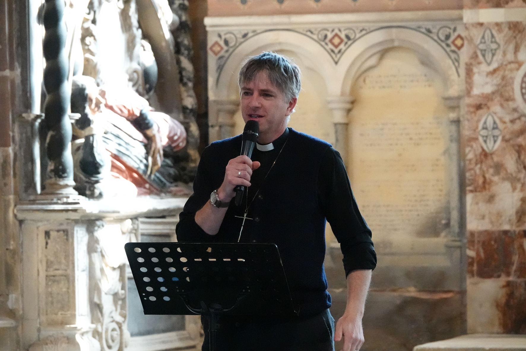Bishop Hugh speaking into a microphone in a church
