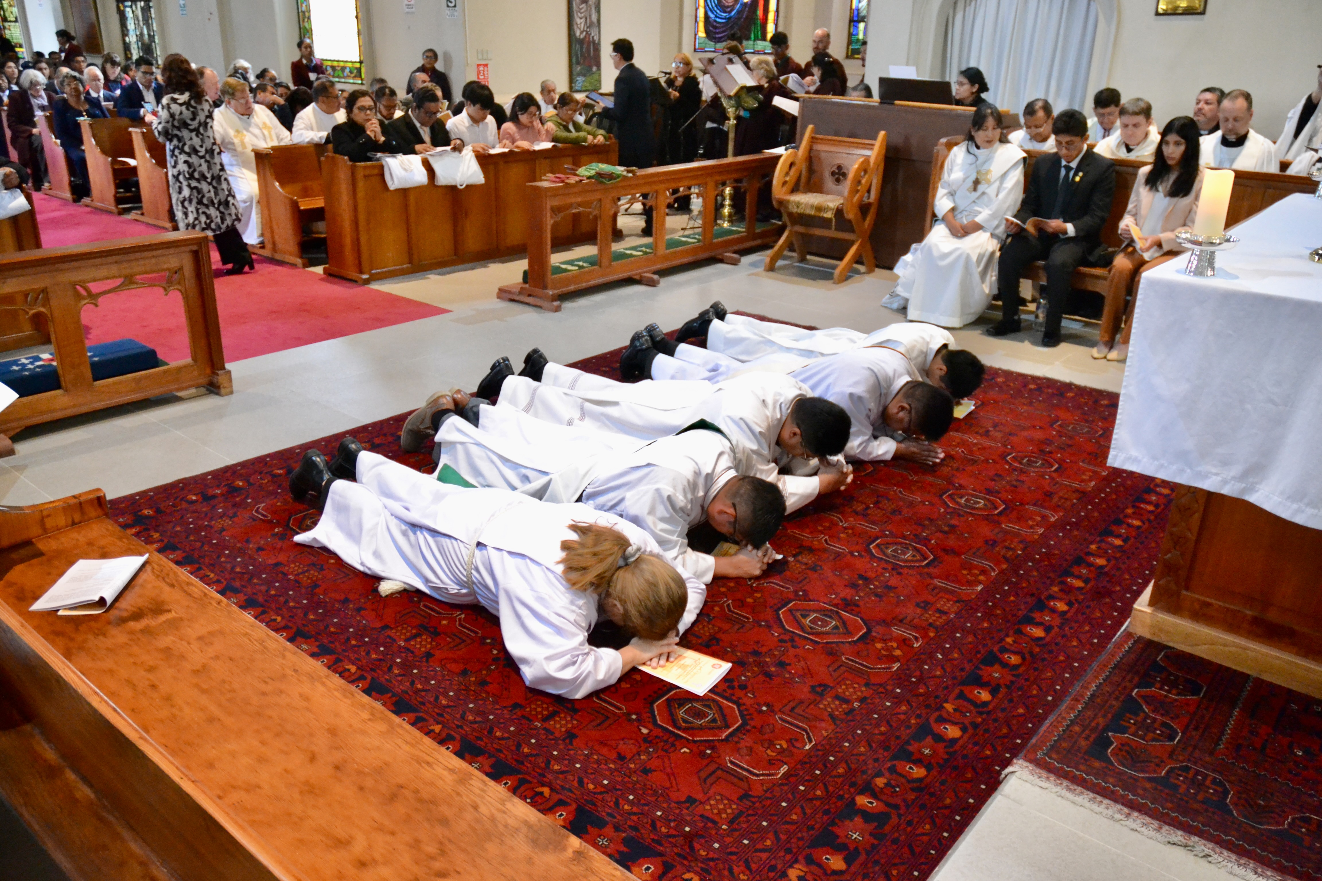 Five deacons lie face down on the floor in front of the altar at Lima Cathedral