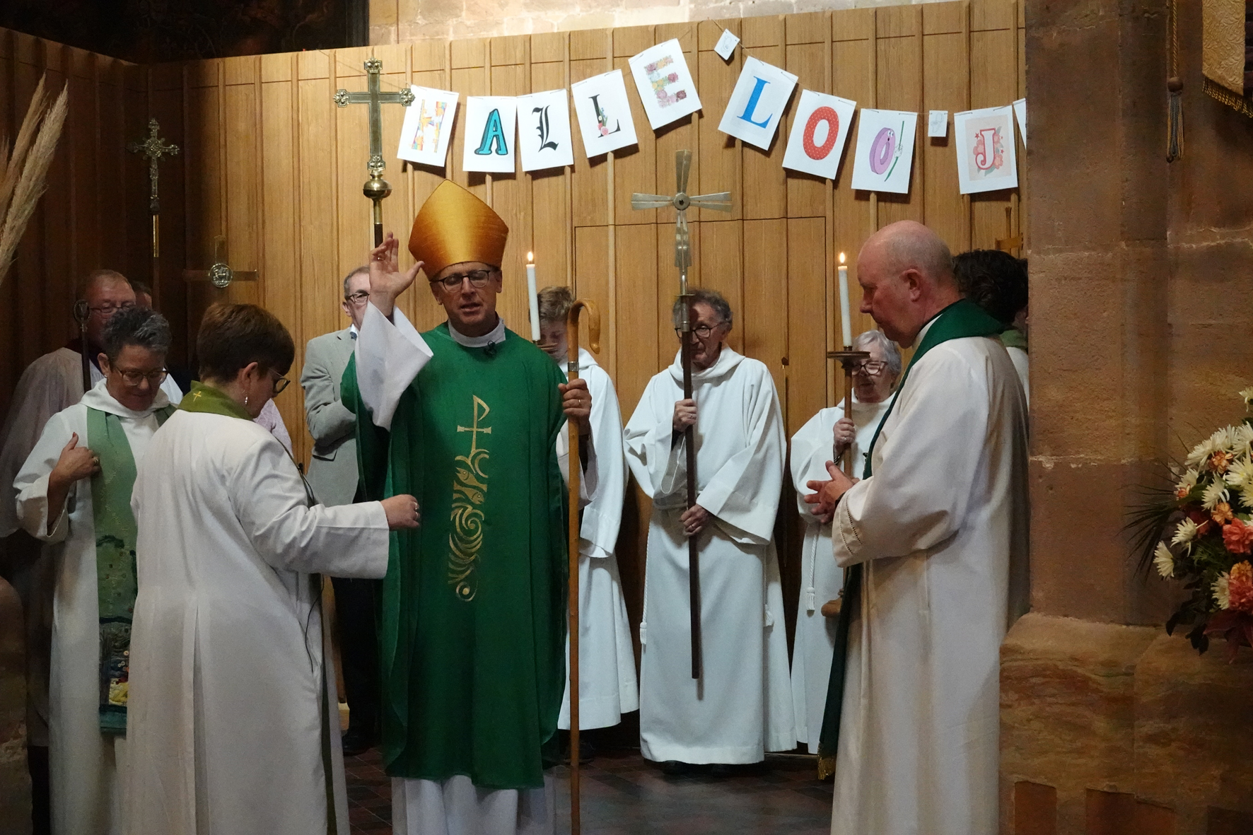 Bishop Martin offering a blessing as he stands in front of the new toilets alongside other clergy