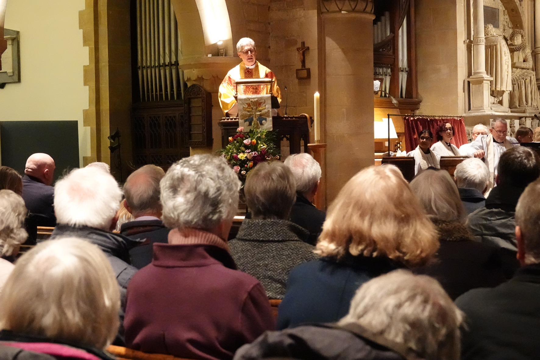 Bishop Martin standing in the pulpit at Eckingon church with the backs of the congregation hears in the foreground