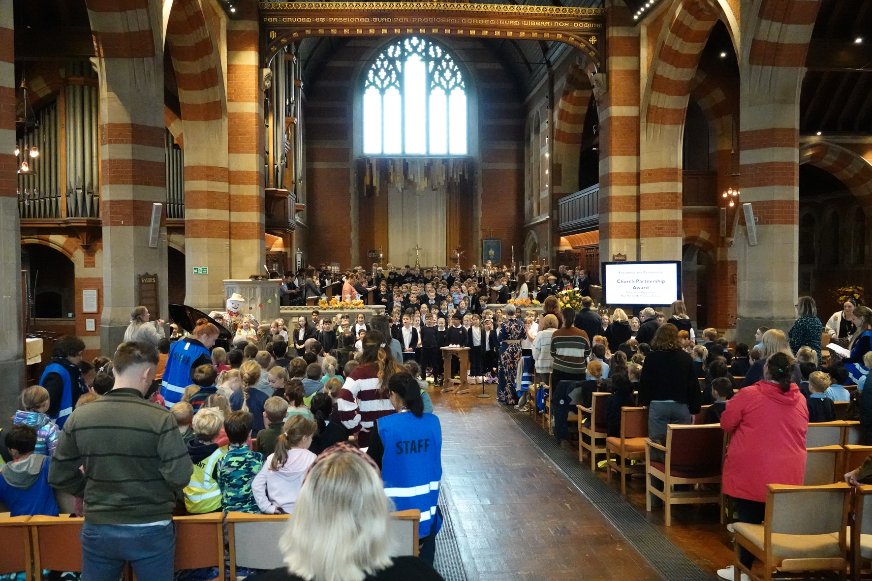 The inside of St Martin's Church with children sat in the chairs facing the altar and others sat on the floor in front of the altar