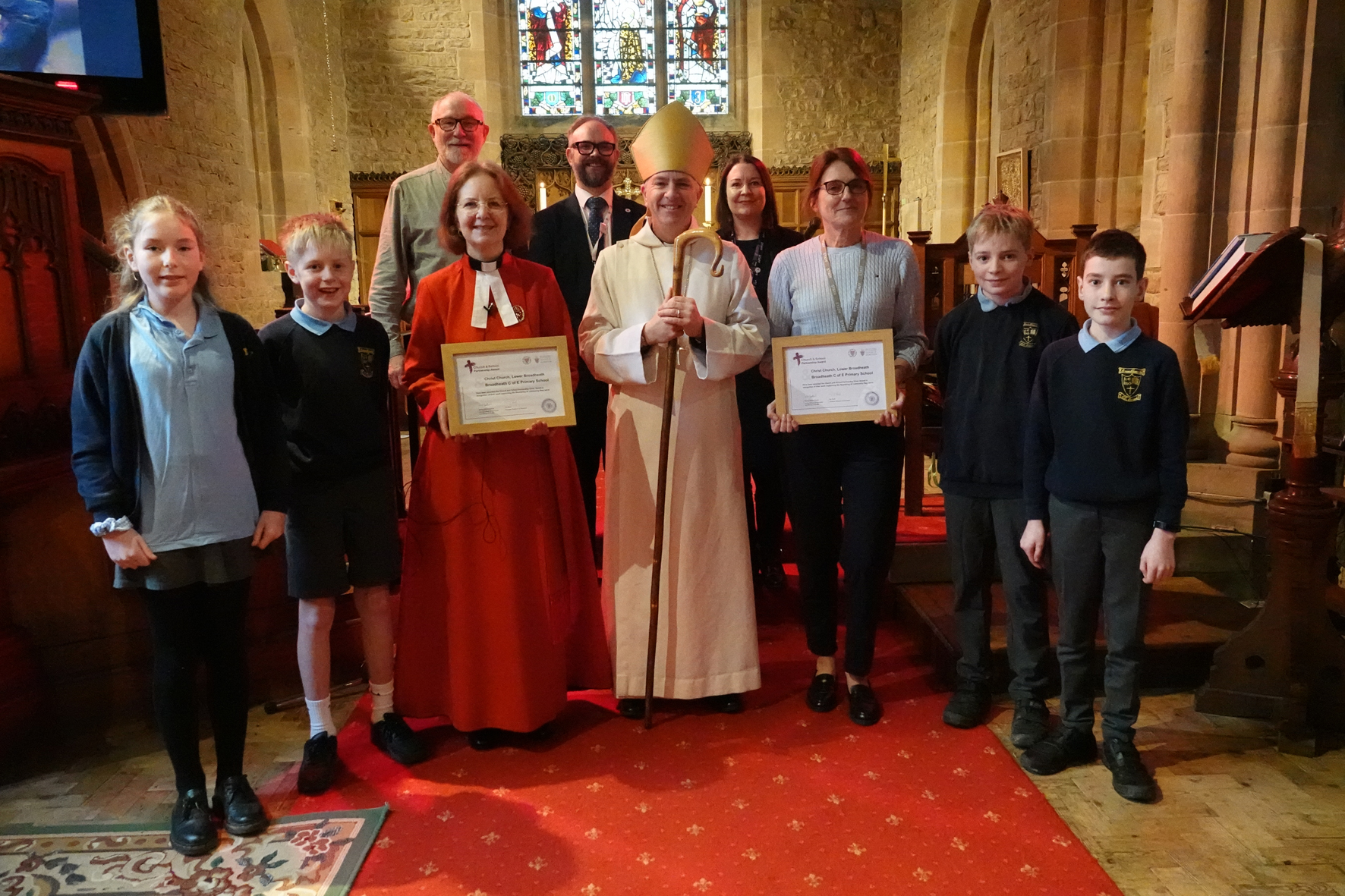 A group of people from Broadheath church and school with Bishop Hugh holding their partnership awards