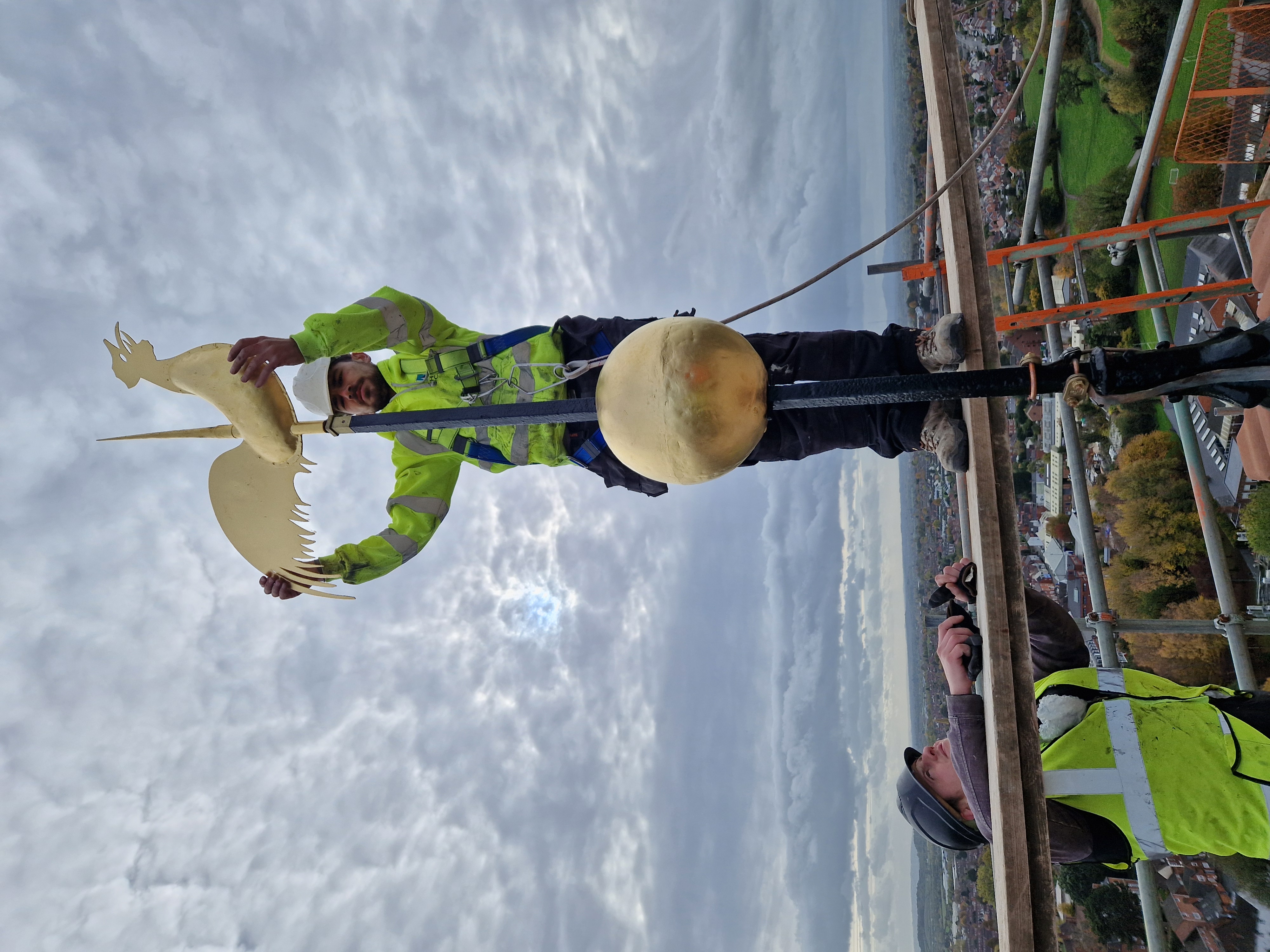 Workman putting a cockerel onto the top of the weathervane