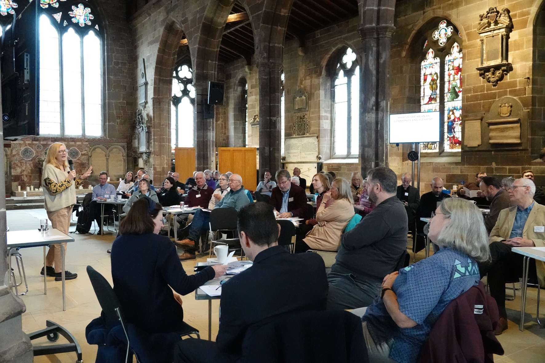 People sat around tables listening to a speaker in St Helen's Church