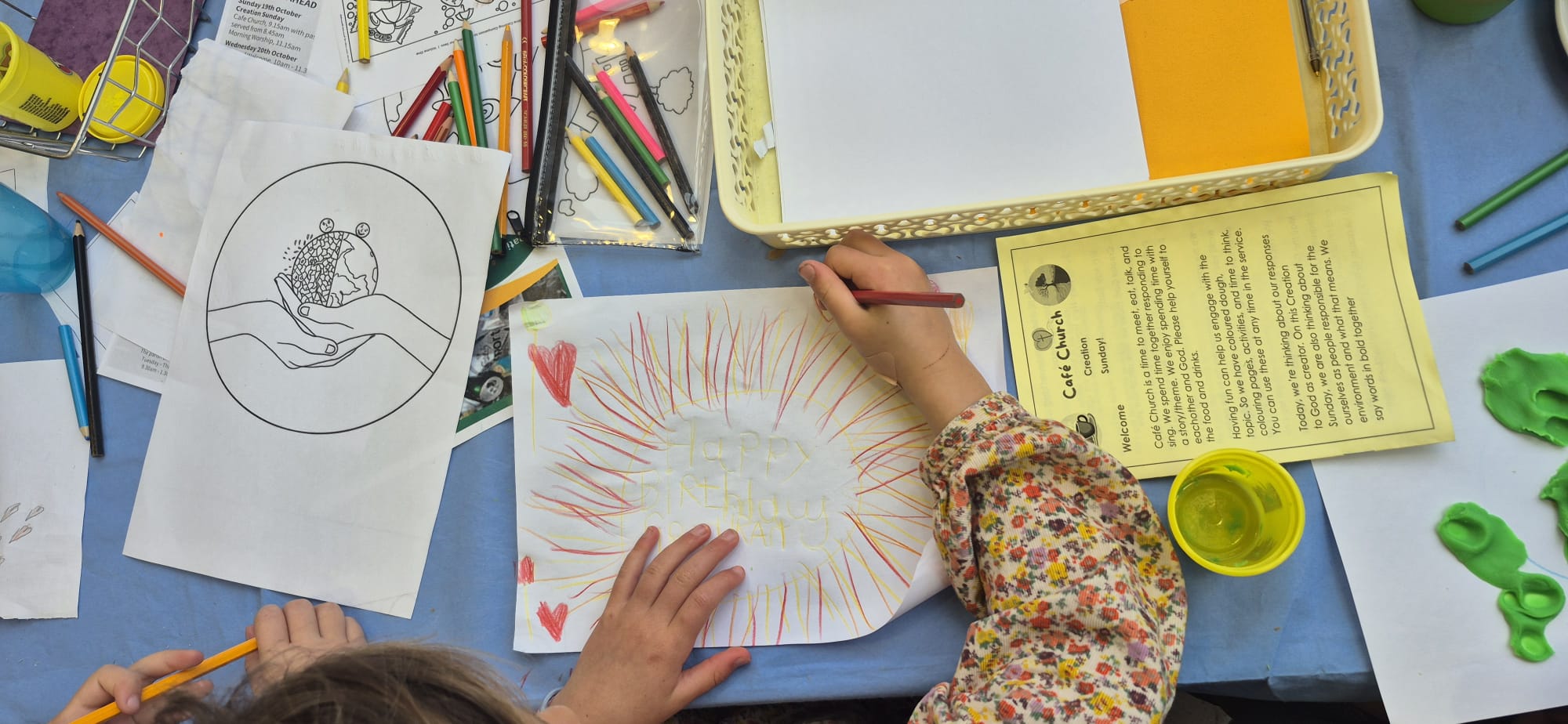 Hands on a table colouring in a poster