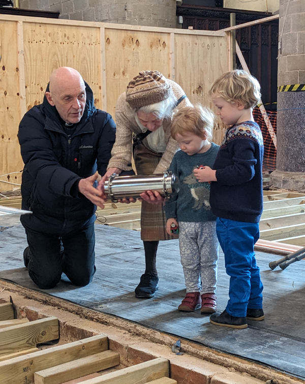 The Revd Corke looks at the time capsule with 92 year old Edwina and two 3 year old children