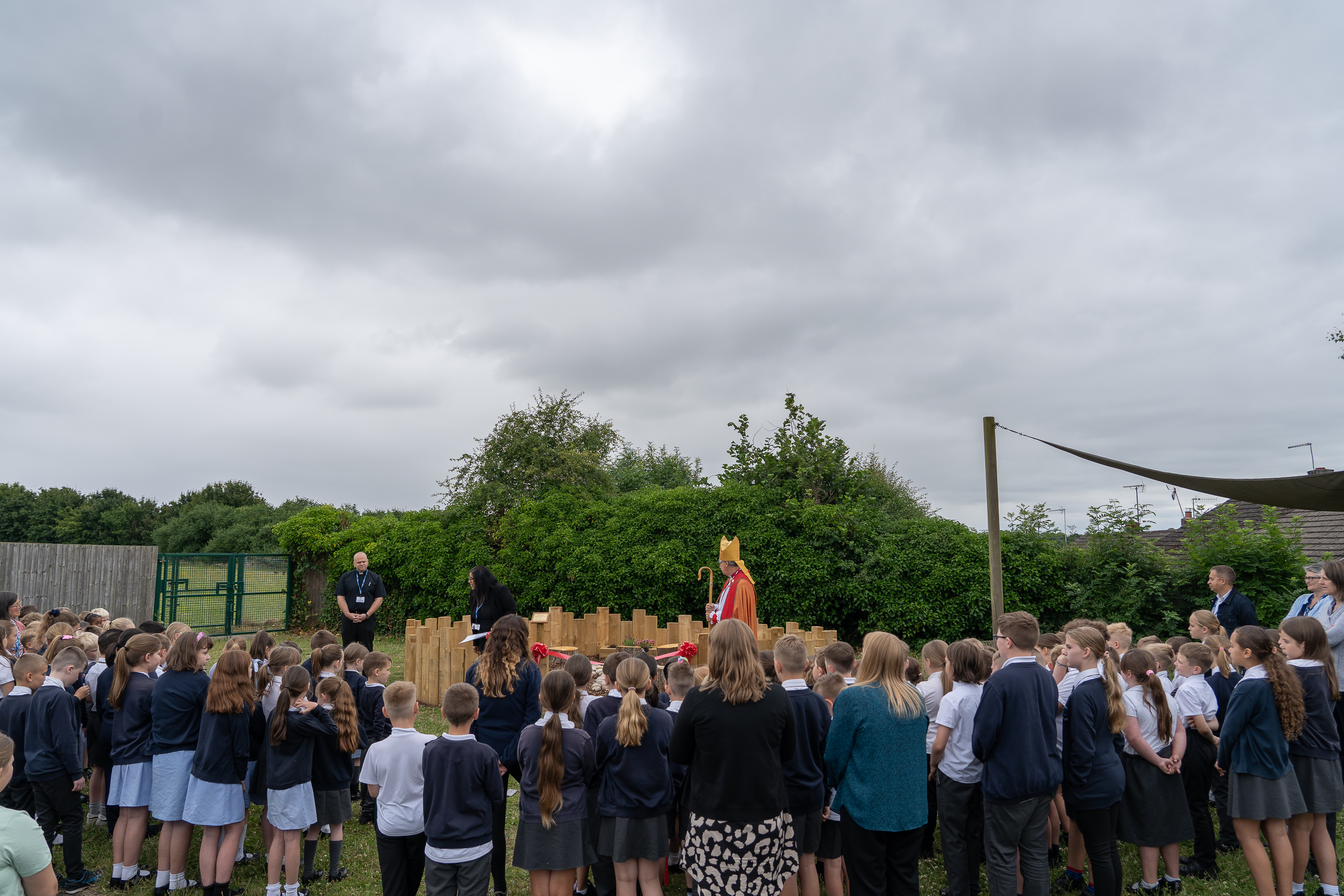 Children and staff gathered around the prayer garden as Bishop Martin opens it