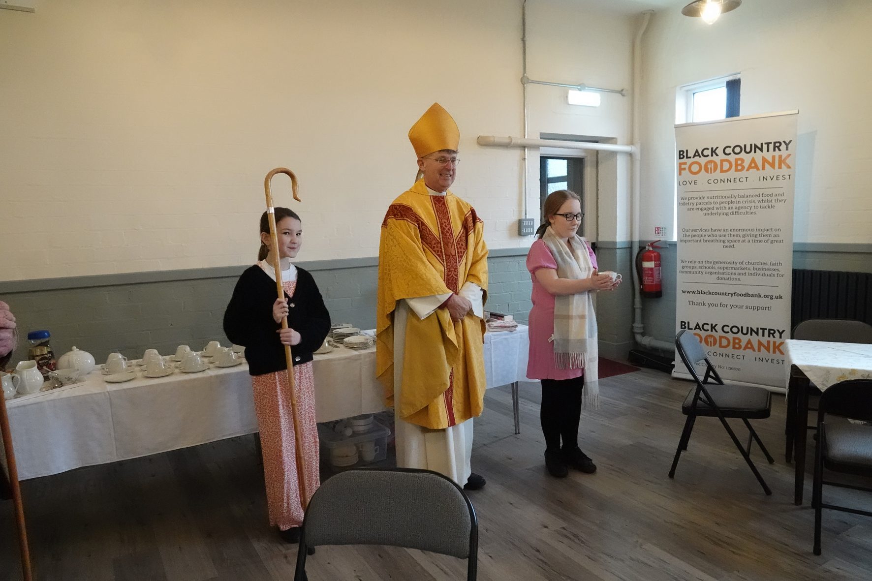 Bishop Martin standing with two younger members of st John's congregation as he blesses the new foodbank