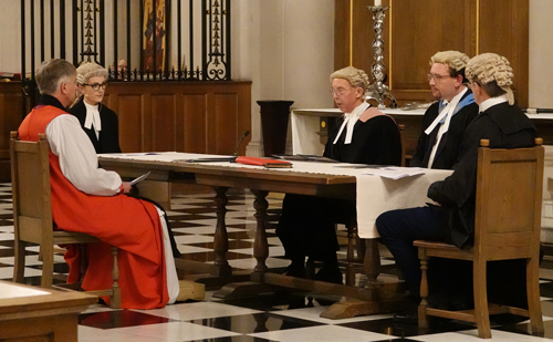 Bishop Hugh sits at  a table with four legal representatives as they decide if processes have been properly followed