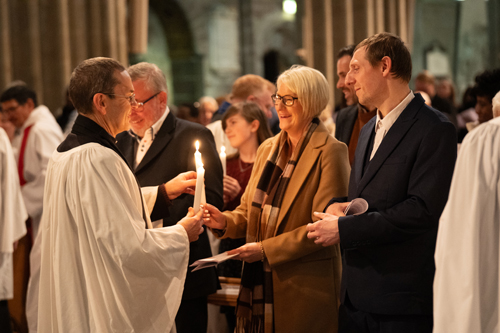 Lady receiving a candle following her confirmation by a member of the clergy