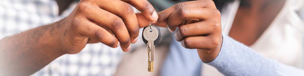 A close up photo of a couple's hands holding up a set of keys for their new home