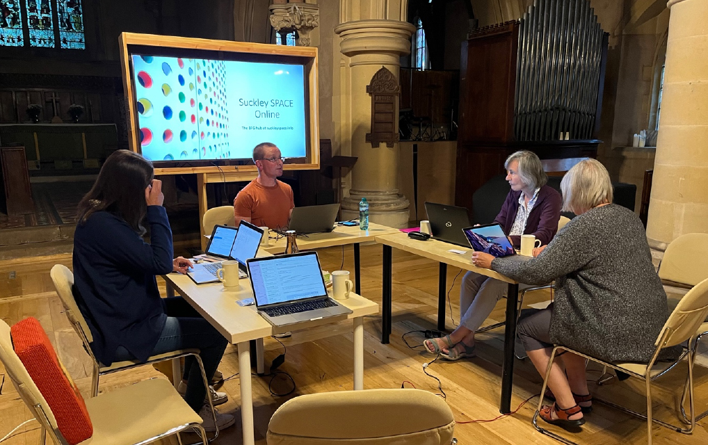 People gathered around desk in Suckley church getting tech support