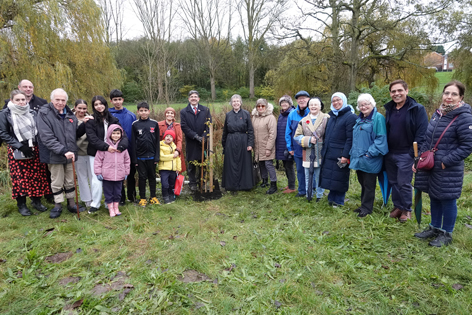 Group of people from different faiths gathered around the tree which has just been planted