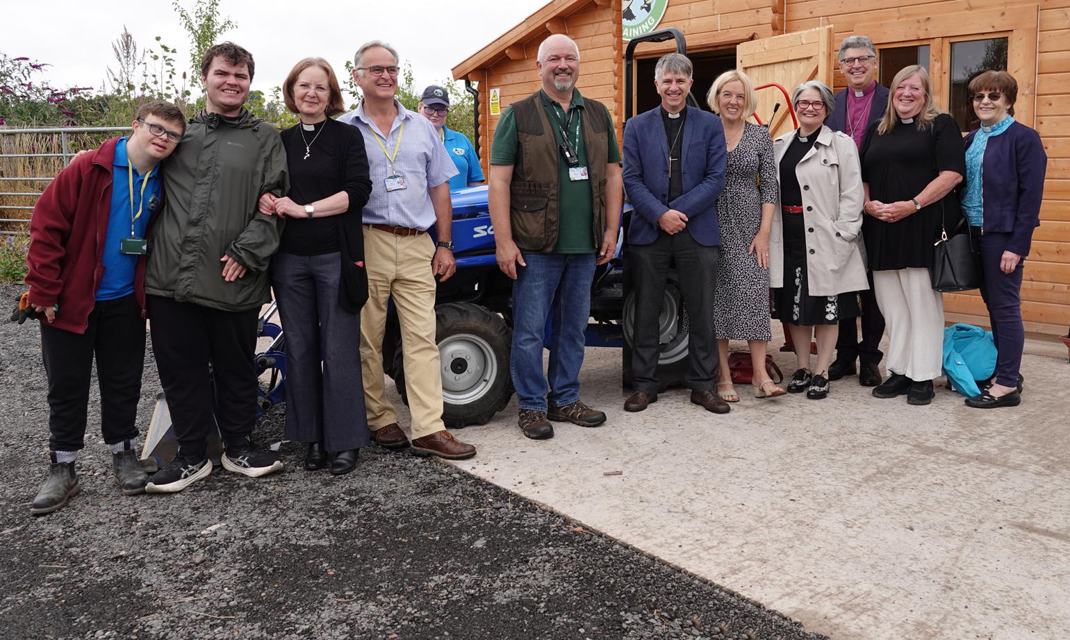 People standing in front of a small tractor outside a Wildgoose training farm barn