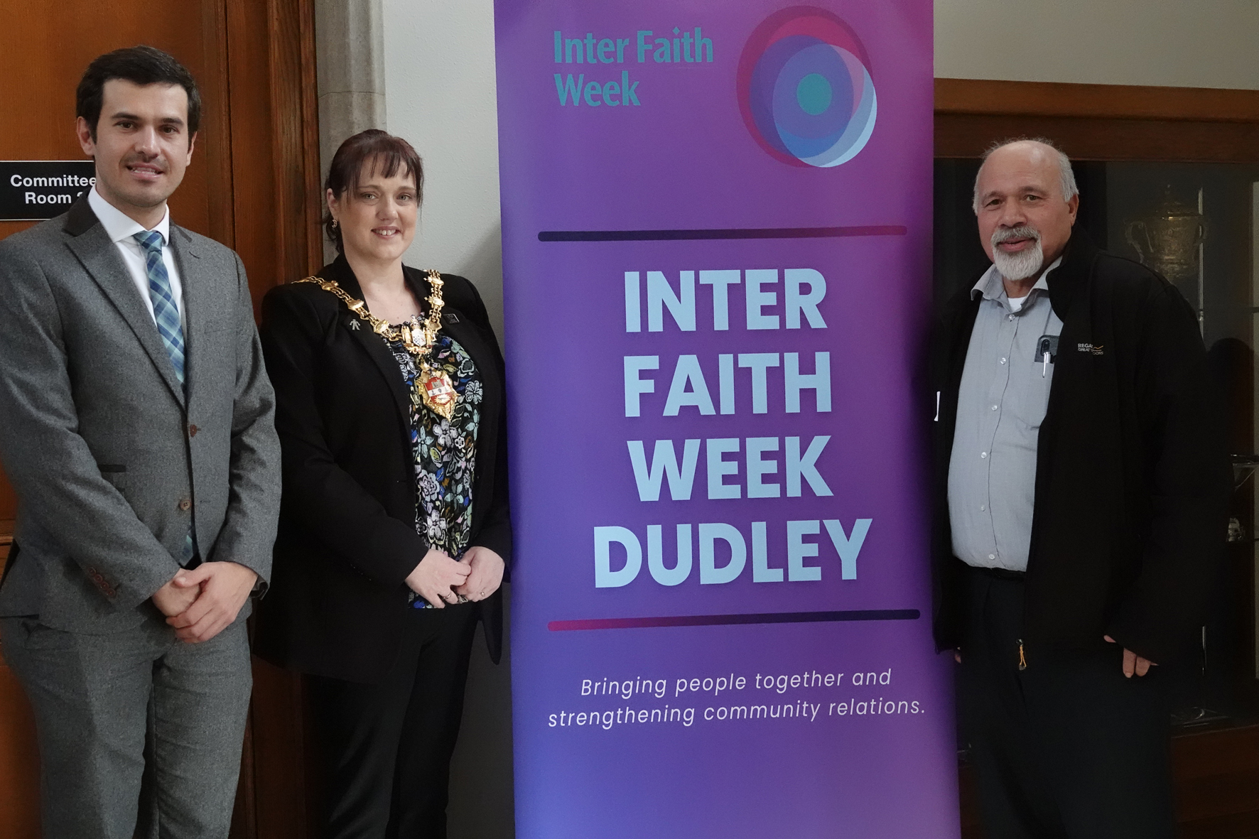 Dudley Mayor standing next to an Interfaith Week banner with two other people