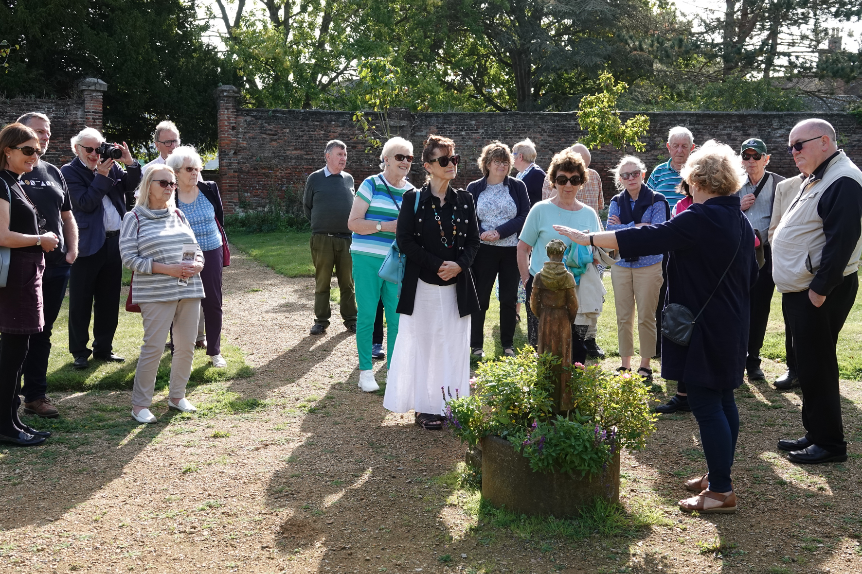 Pilgrims in the Franciscan gardens looking at a statue of St Francis