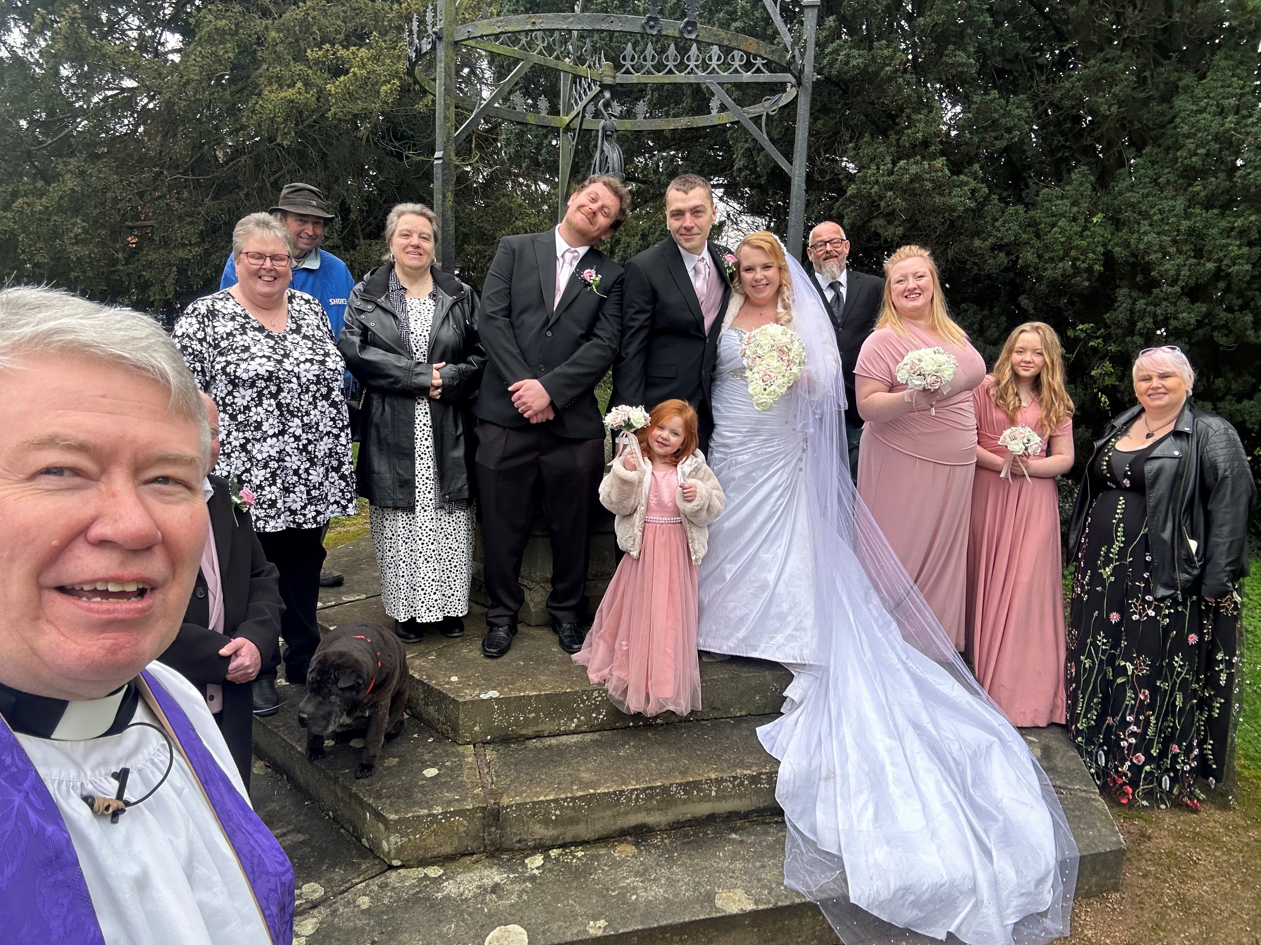 Vicar Gary Crellin takes a photo with the wedding party outside the church