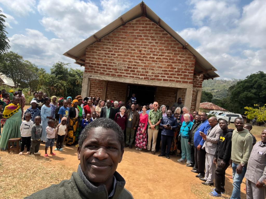 A group of people outside a building in Mrogoro while one man takes a selfie