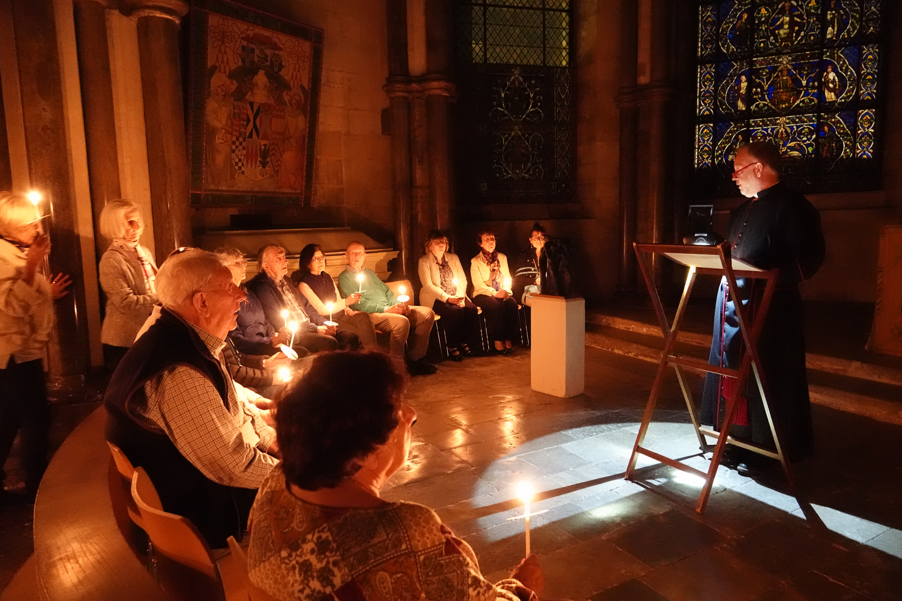 Pilgrims sitting in a circle in candlelight listening to the Dean