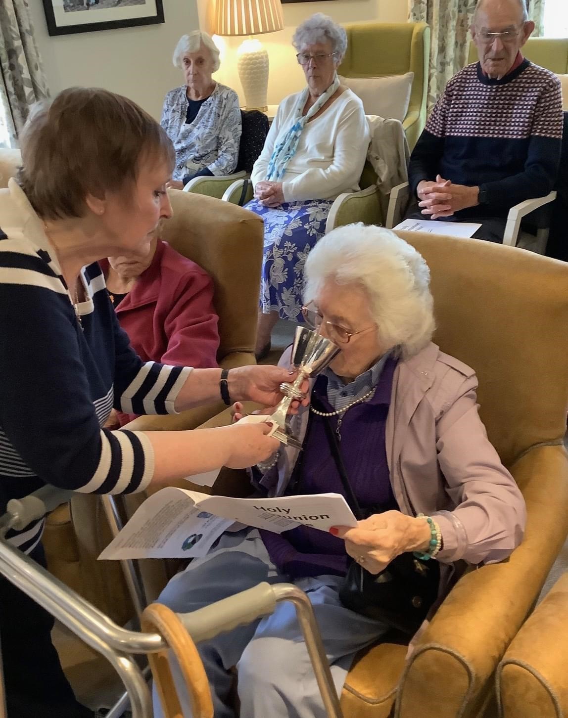 A member of Lapa's congregation helps a care home resident to receive communion.