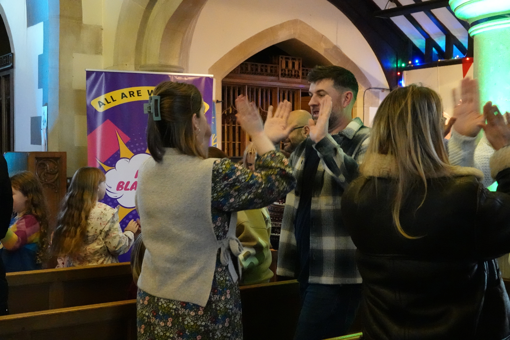 People standing in pews giving each other a double hi-five
