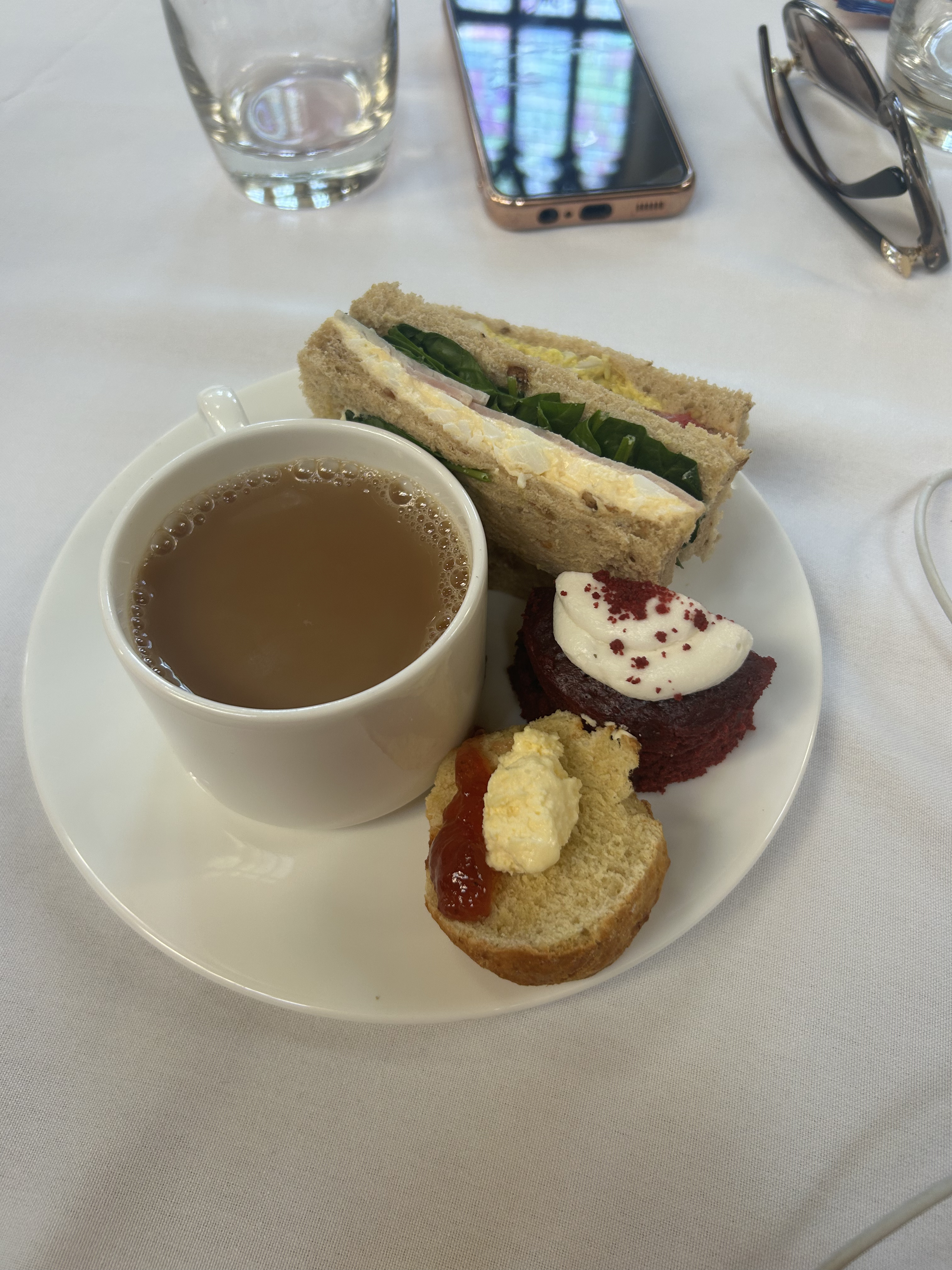 Plate with a cup of tea, a sandwich and two small cakes
