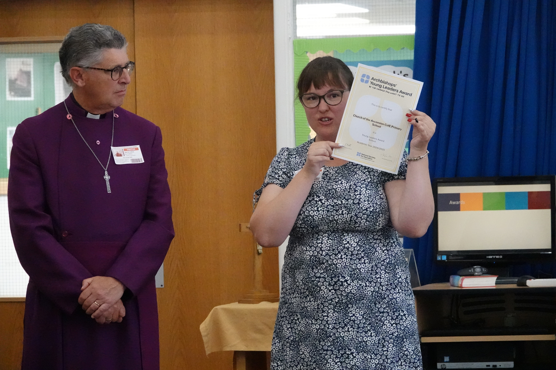 Bishop Martin stood looking at Sian Morgan who is holding the Archbishops' Award certificate