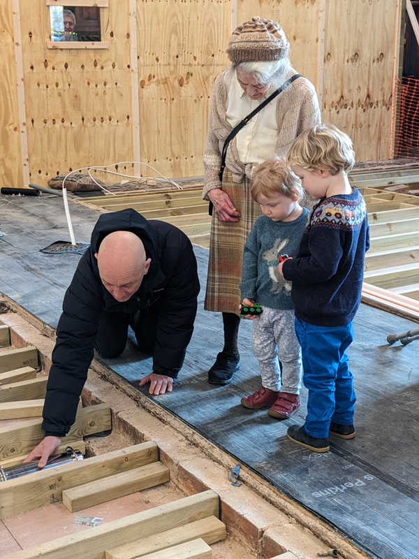 Rod corke puts the capsule in the floor watched on by Edwina and the children