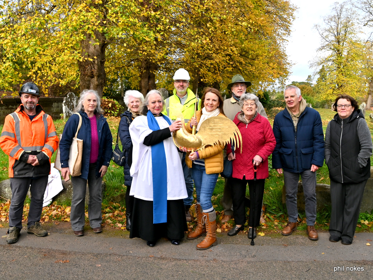 Lay Minister Hilda Roxborough holding a golden cockerel surrounded by a group of people