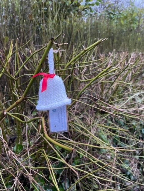 Close up of a knitted bell hanging on a hedge