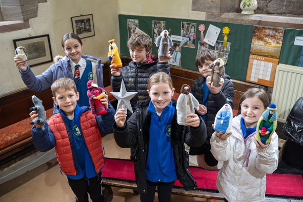 Children from Clifton school holding up knitted nativity characters