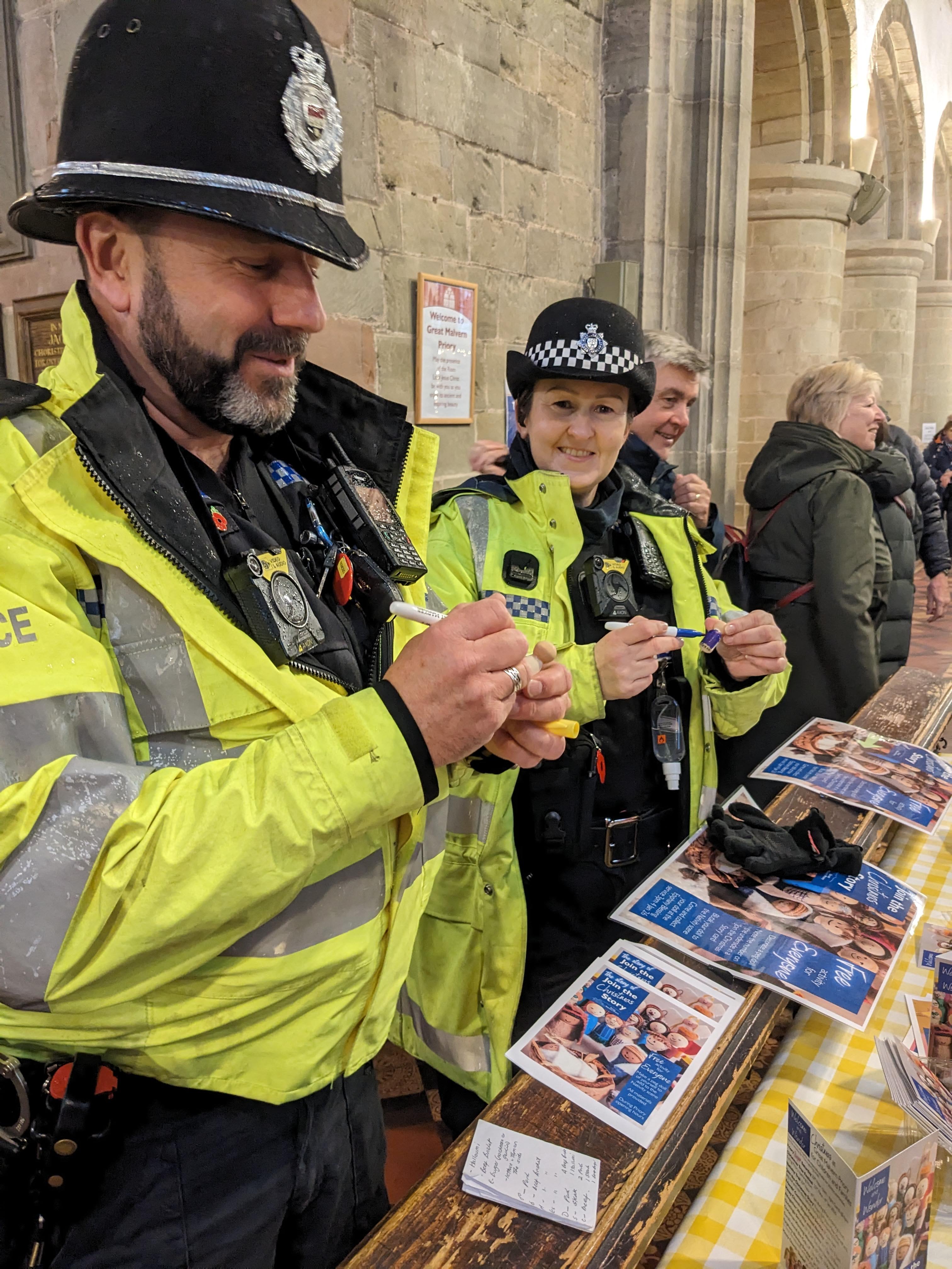 Male and female police officers decorate a peg doll