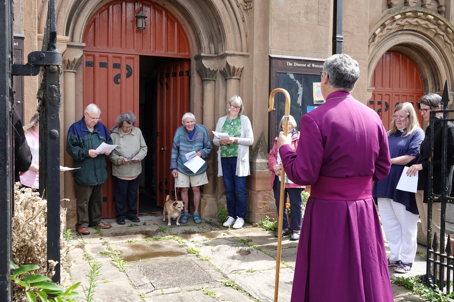 Bishop Martin with a group of people praying outside the door of St Clement's Church in Worcester