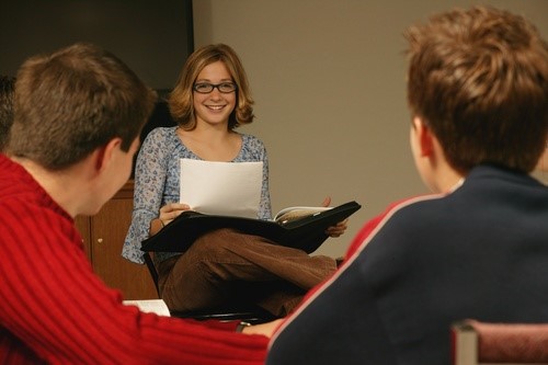 Person with folder talking to two other people